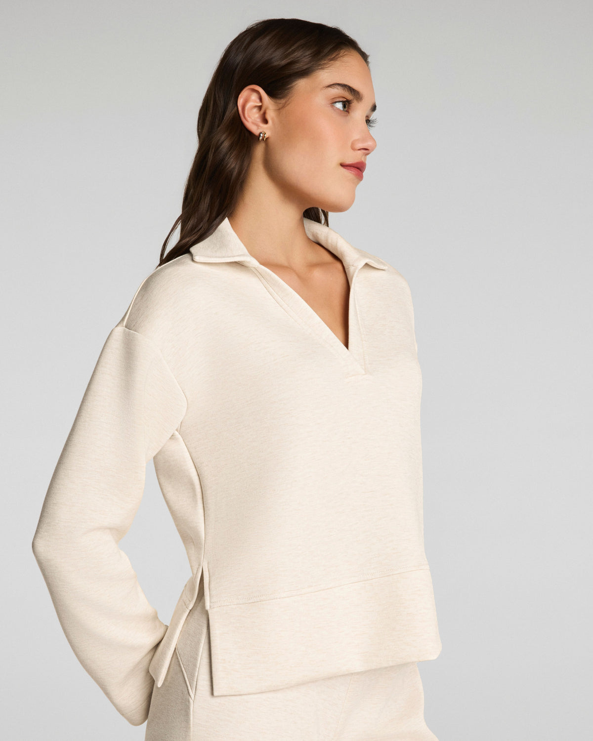Woman wearing a SPANX cream-colored top against a plain background