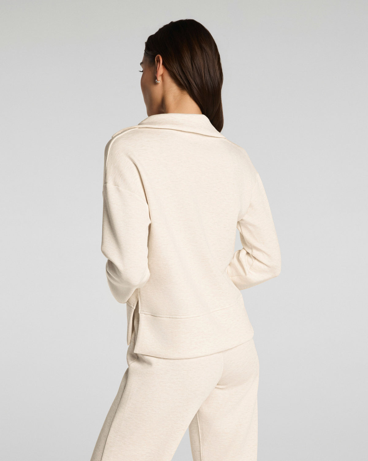 Woman wearing a SPANX beige suit on a plain background
