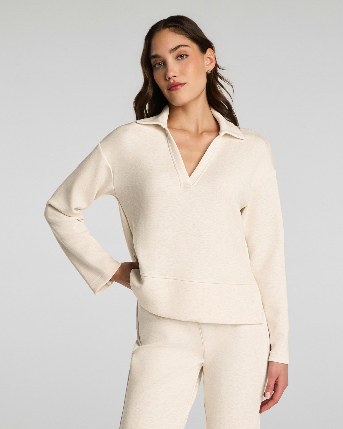 Woman wearing a cream-colored outfit against a plain background