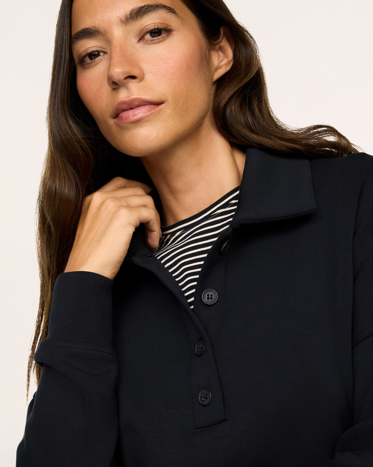 Model wearing SPANX Rugby Shirt in Very Black close up view of buttons and white background.