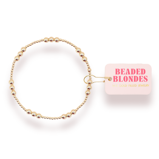 Gold beaded bracelet with 'Beaded Blondes' packaging on a white background