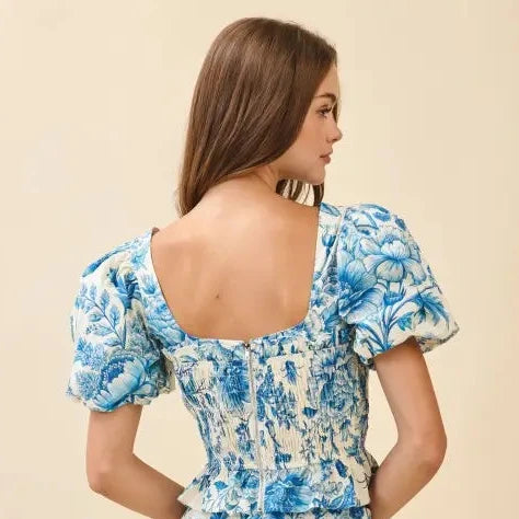 Woman wearing a blue floral top against a beige background