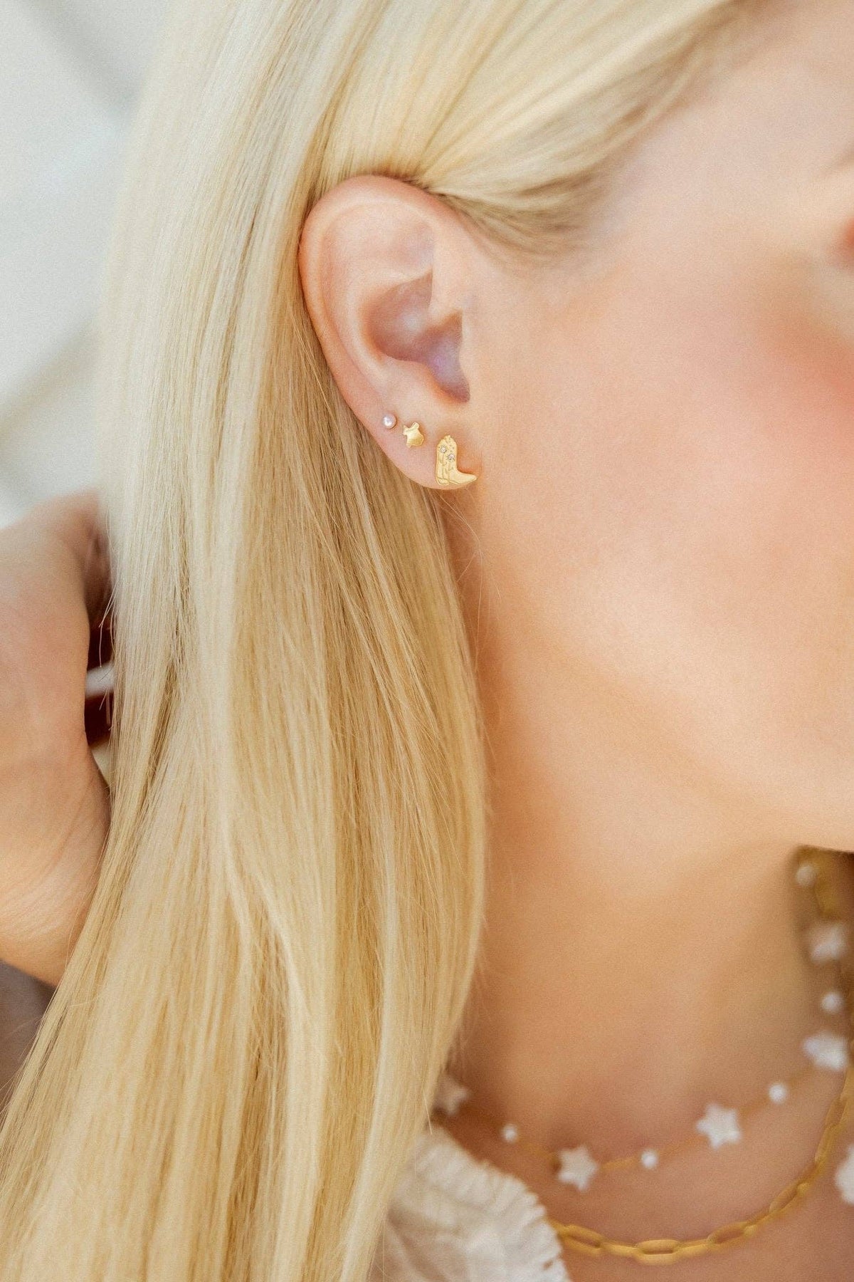 Close-up of a person wearing gold earrings with star designs.