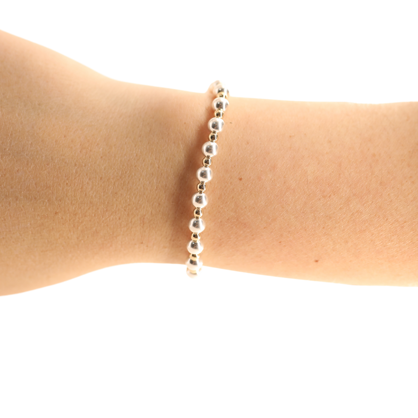 A delicate silver beaded bracelet worn on a person's wrist, shown against a plain white background.