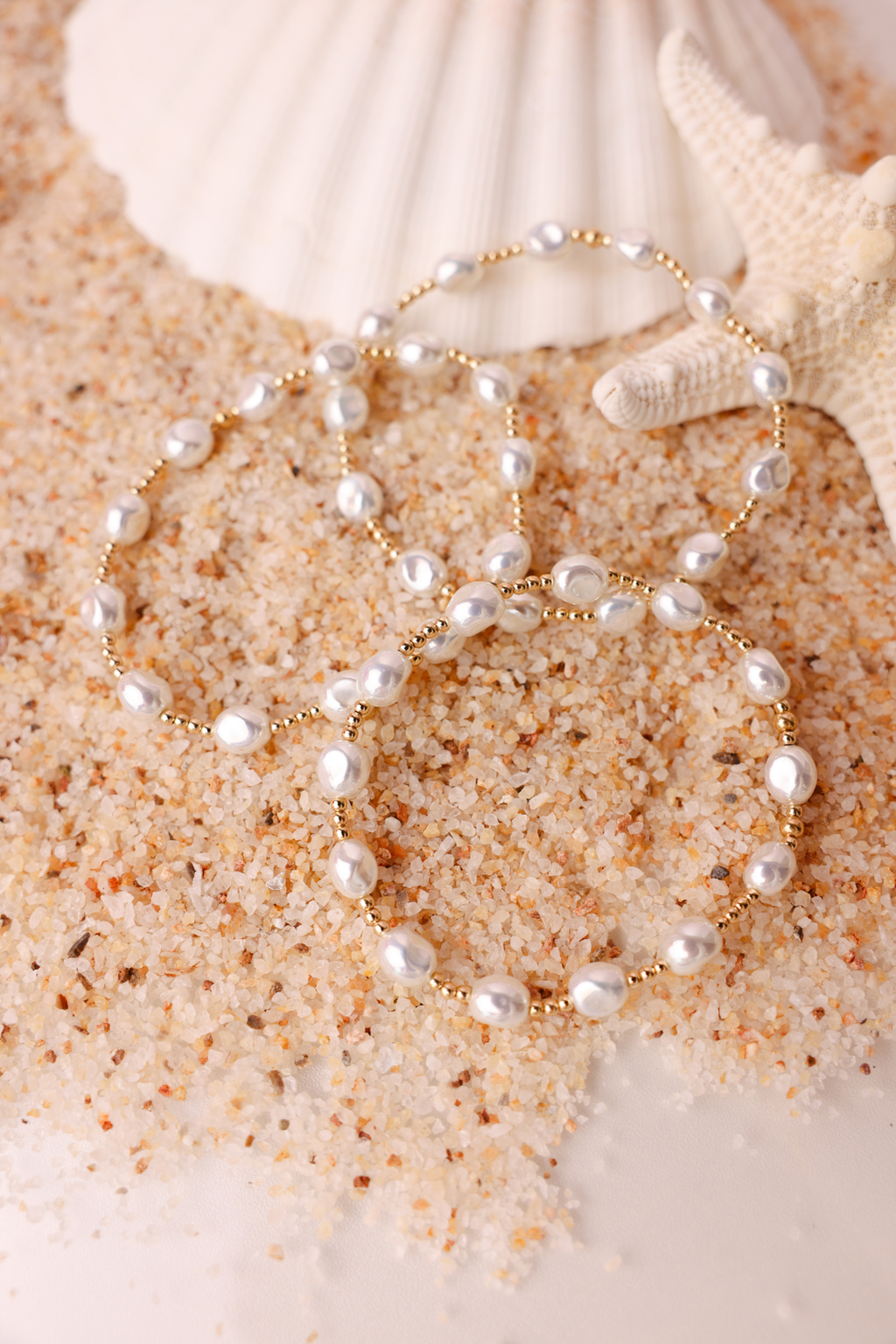 Pearl necklace on sand with seashells