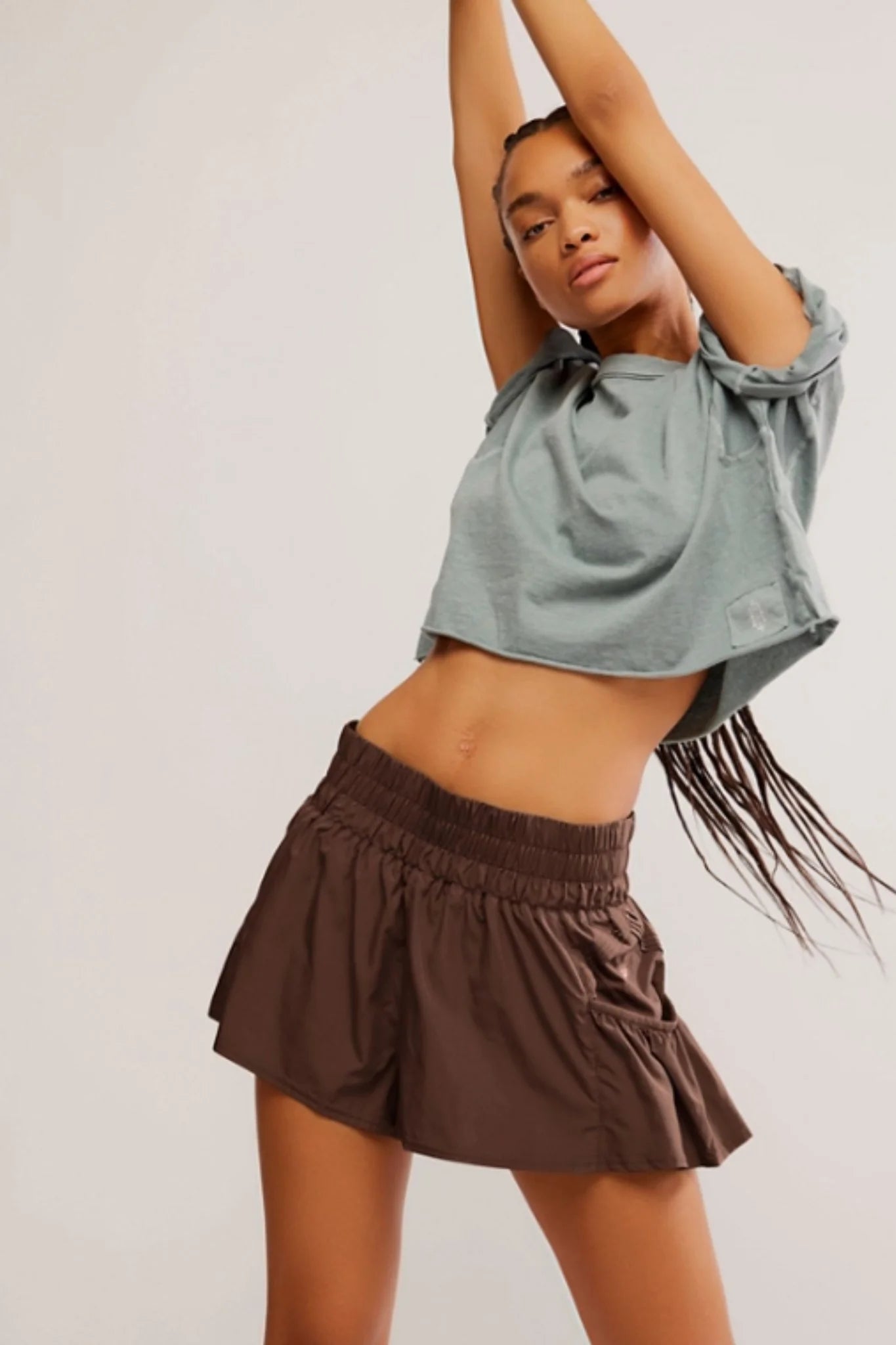 Woman wearing a light blue top and brown shorts against a plain background