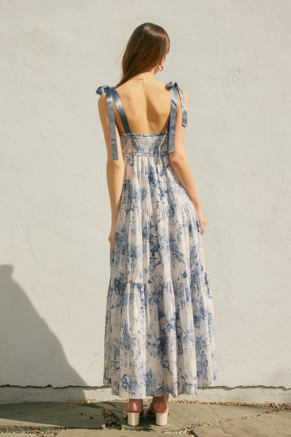 Woman wearing a floral dress against a plain wall