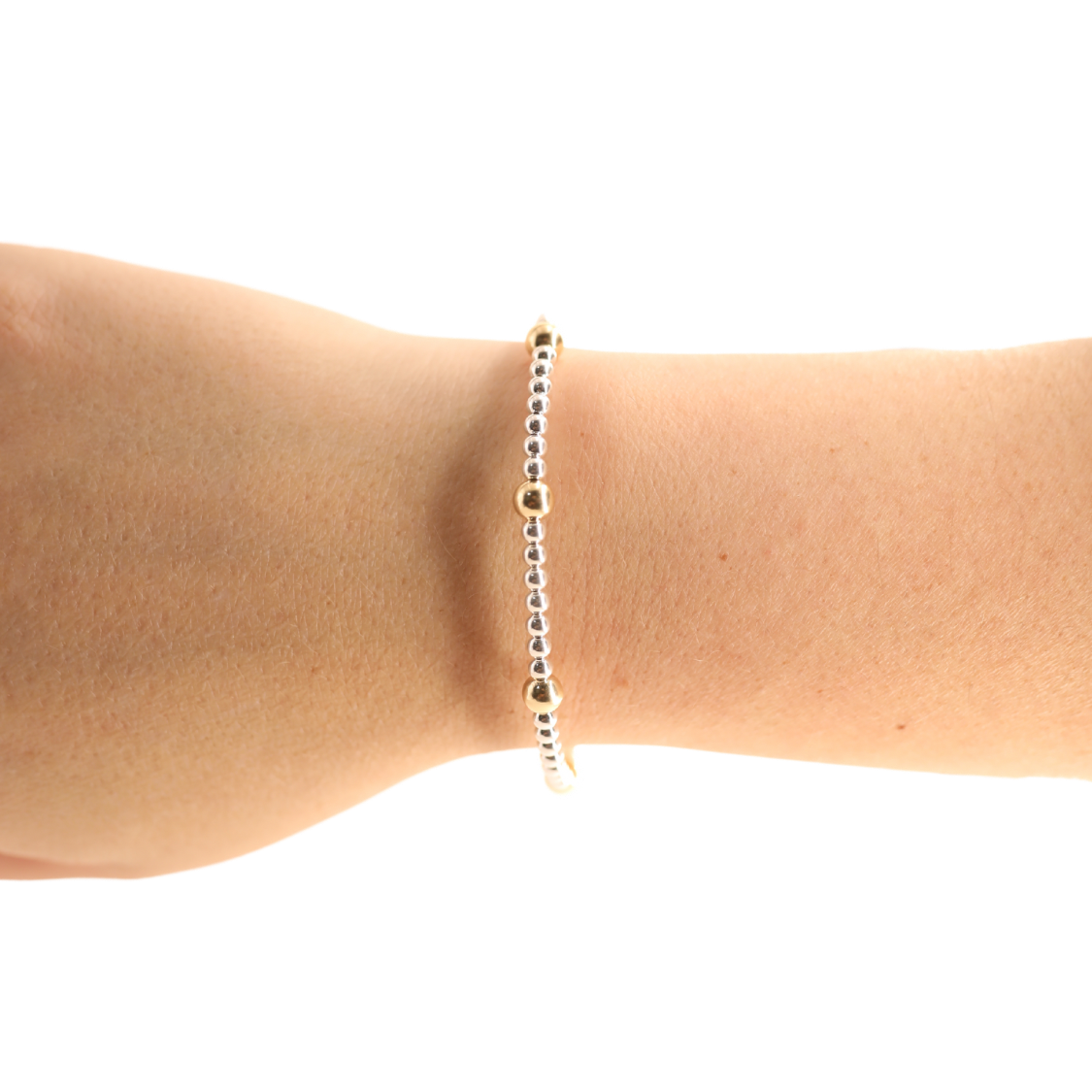 Gold bracelet on a wrist against a white background