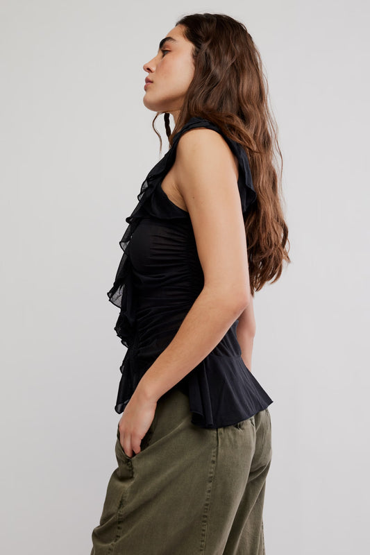 Model wearing black flowy tank top with green jeans facing the side