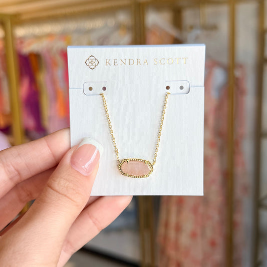 Hand holding a card with a gold necklace on it, with a blurred background