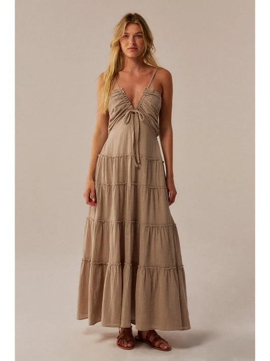 Woman wearing a beige tiered dress against a plain background