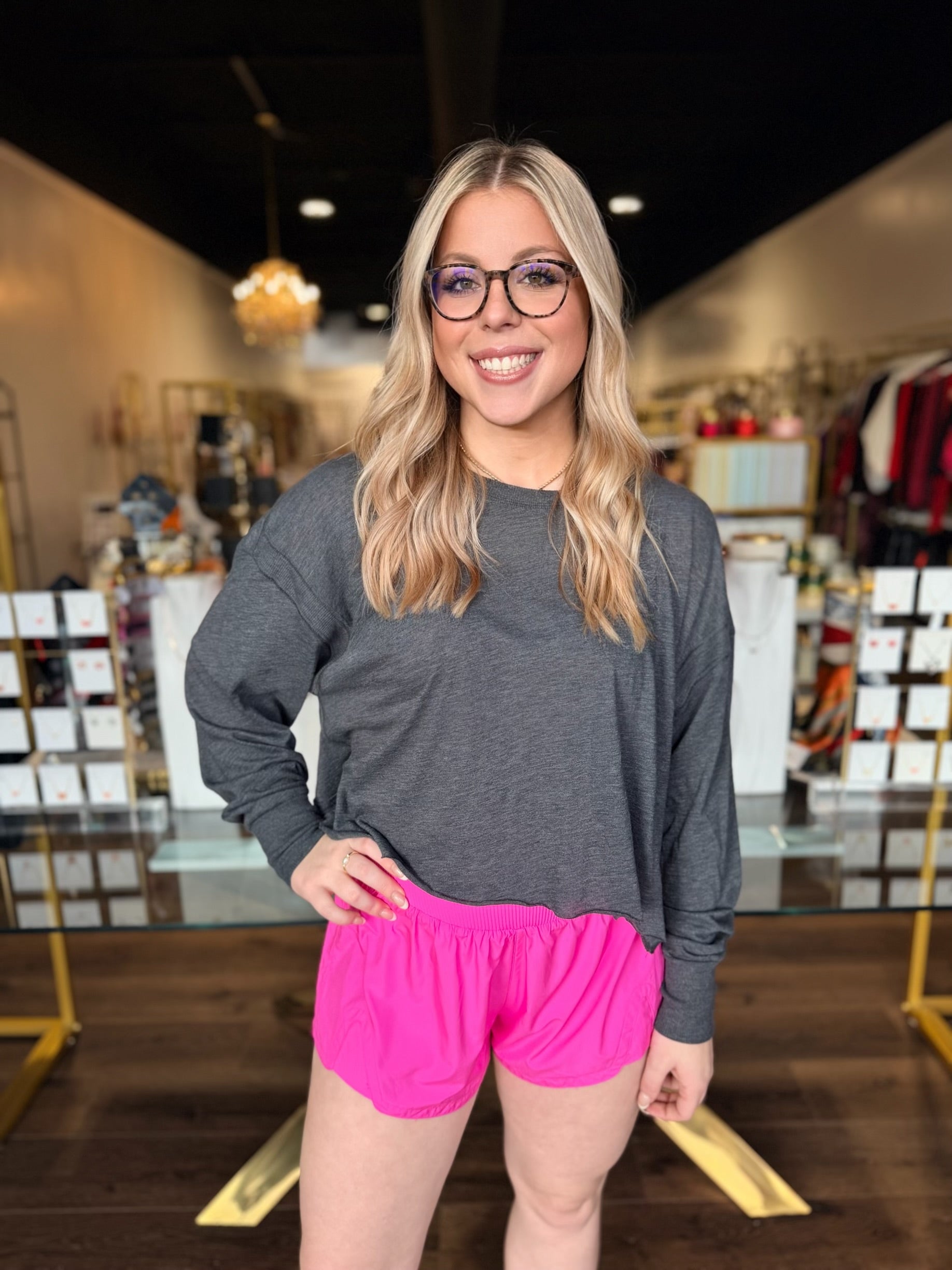 Woman wearing a gray long-sleeve shirt and pink shorts in a store setting
