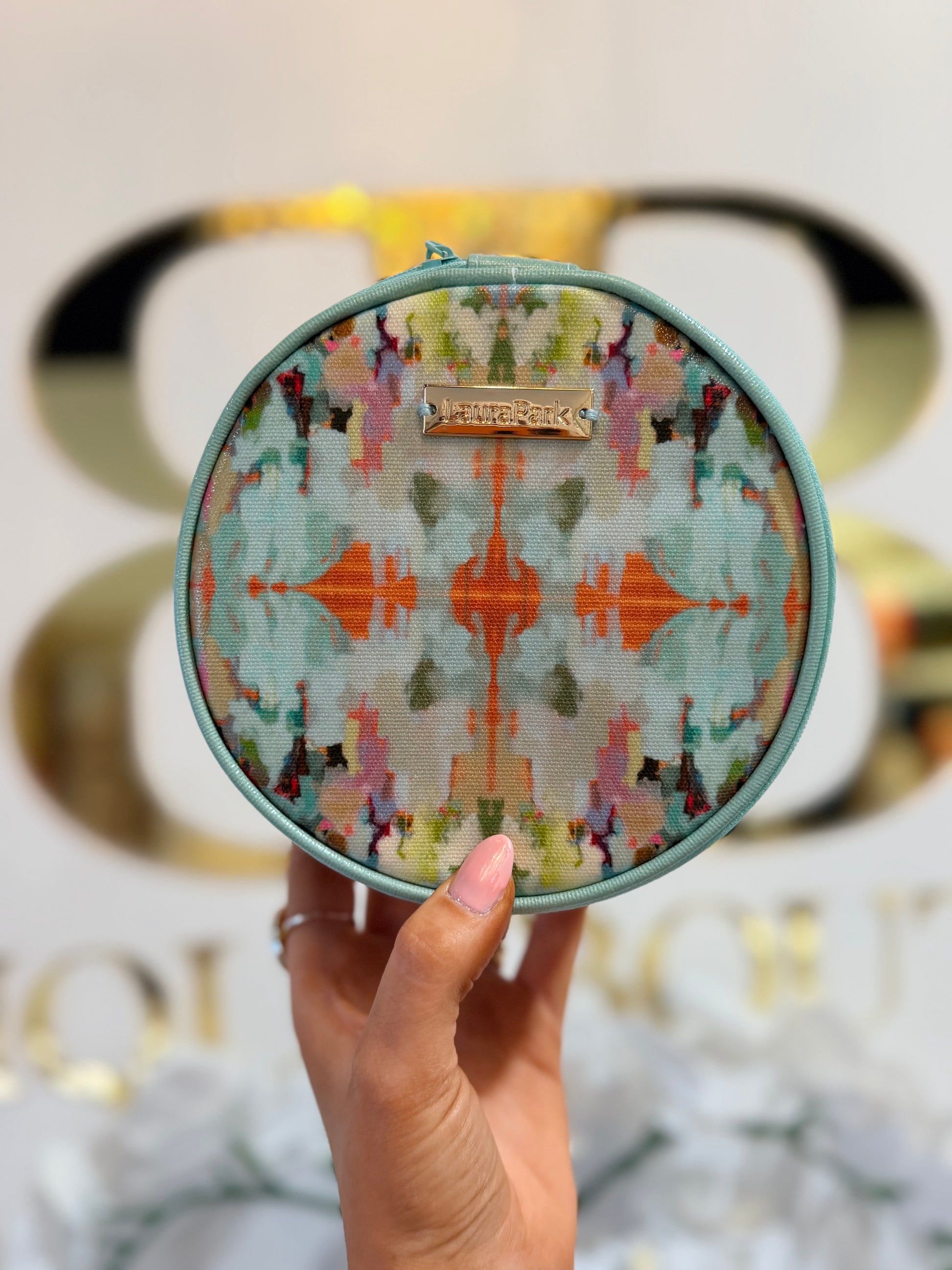Round colorful patterned pouch held by a hand with a blurred background
