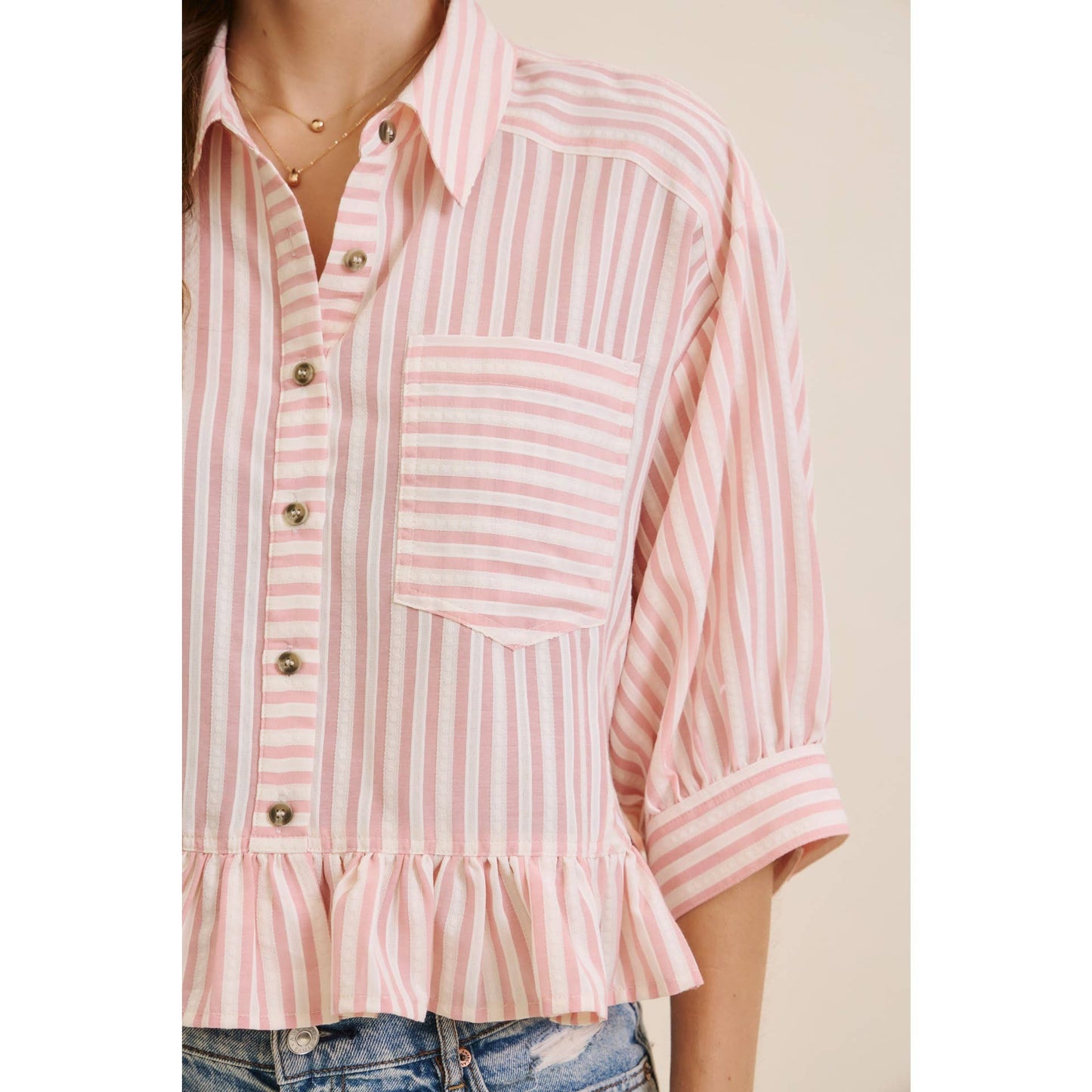 Pink and white striped shirt with ruffled hem on a plain background