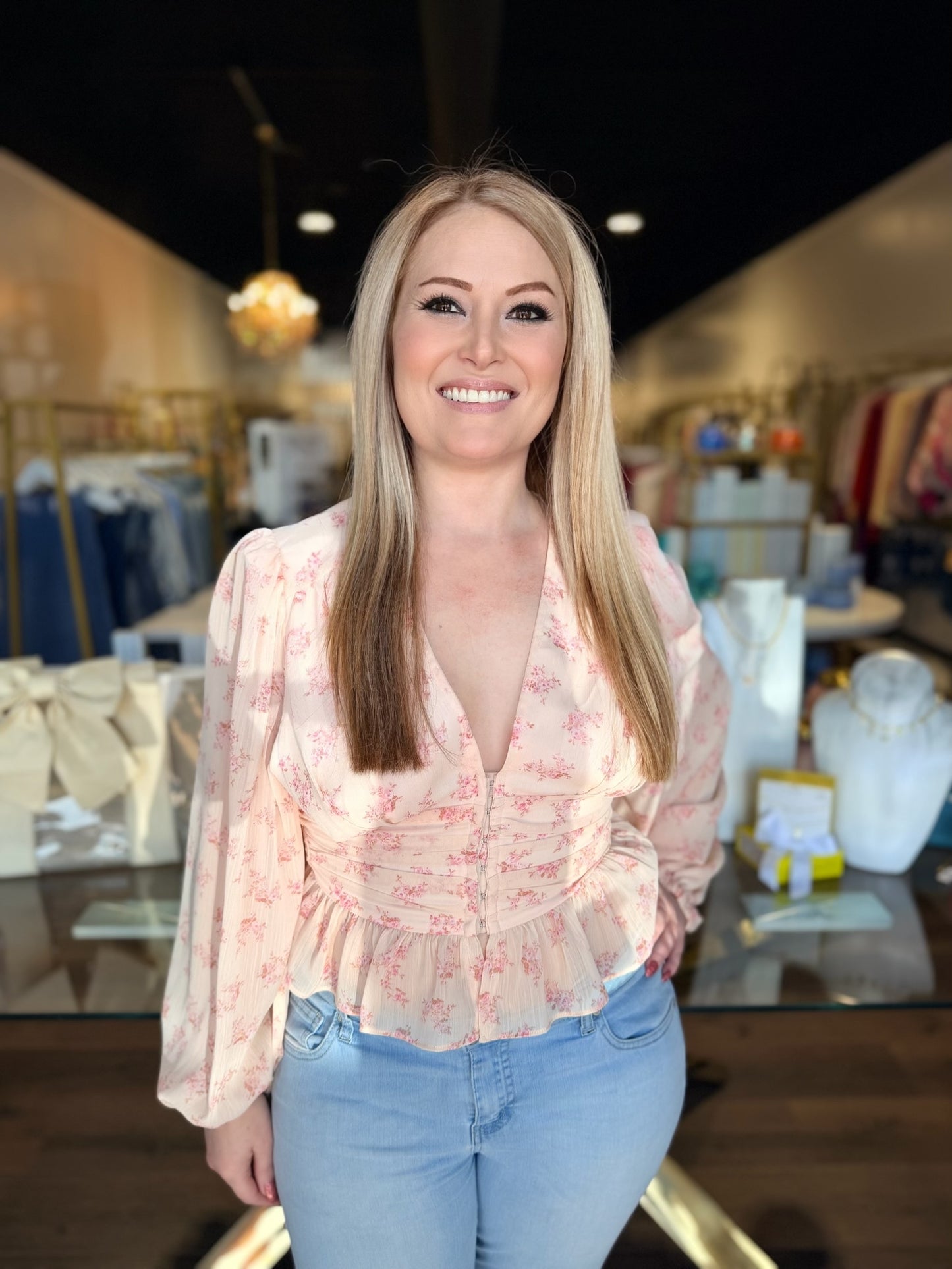 Woman wearing a floral blouse and jeans in a store setting