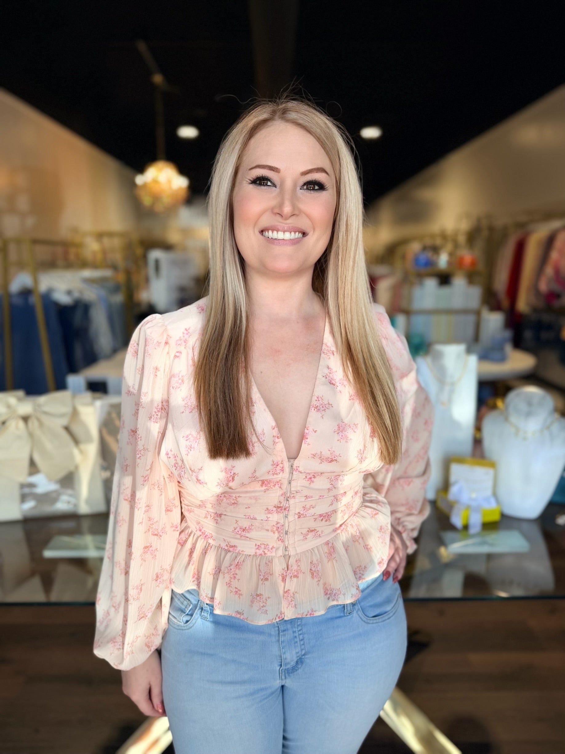 Woman wearing a floral blouse and jeans in a store setting