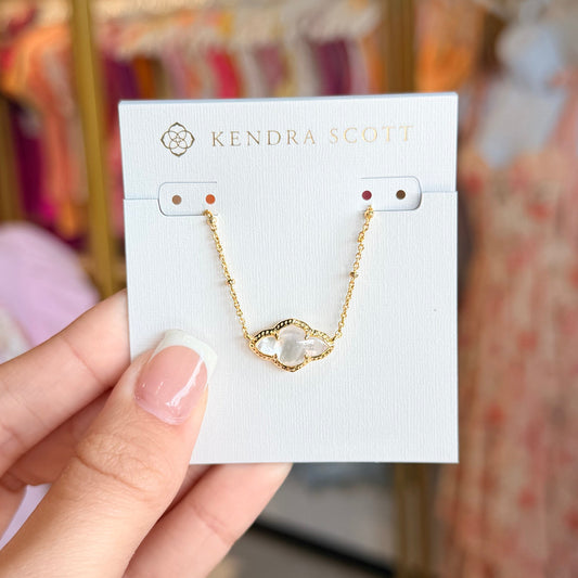 Hand holding a card with a gold necklace on it, with a blurred background