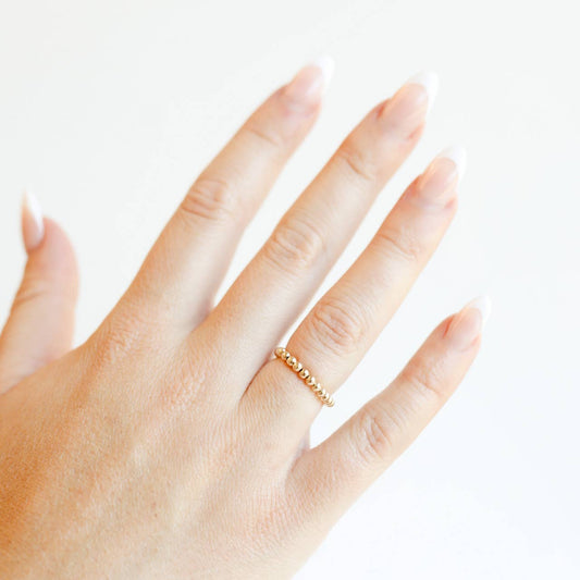 Hand wearing a gold ring on a white background