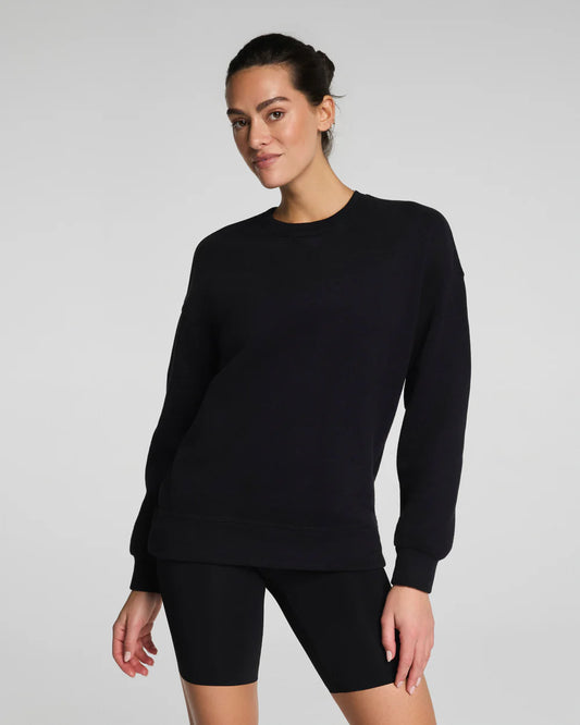 Model wearing black SPANX® BoostUp Cotton Fleece Crewneck Tunic with white background.