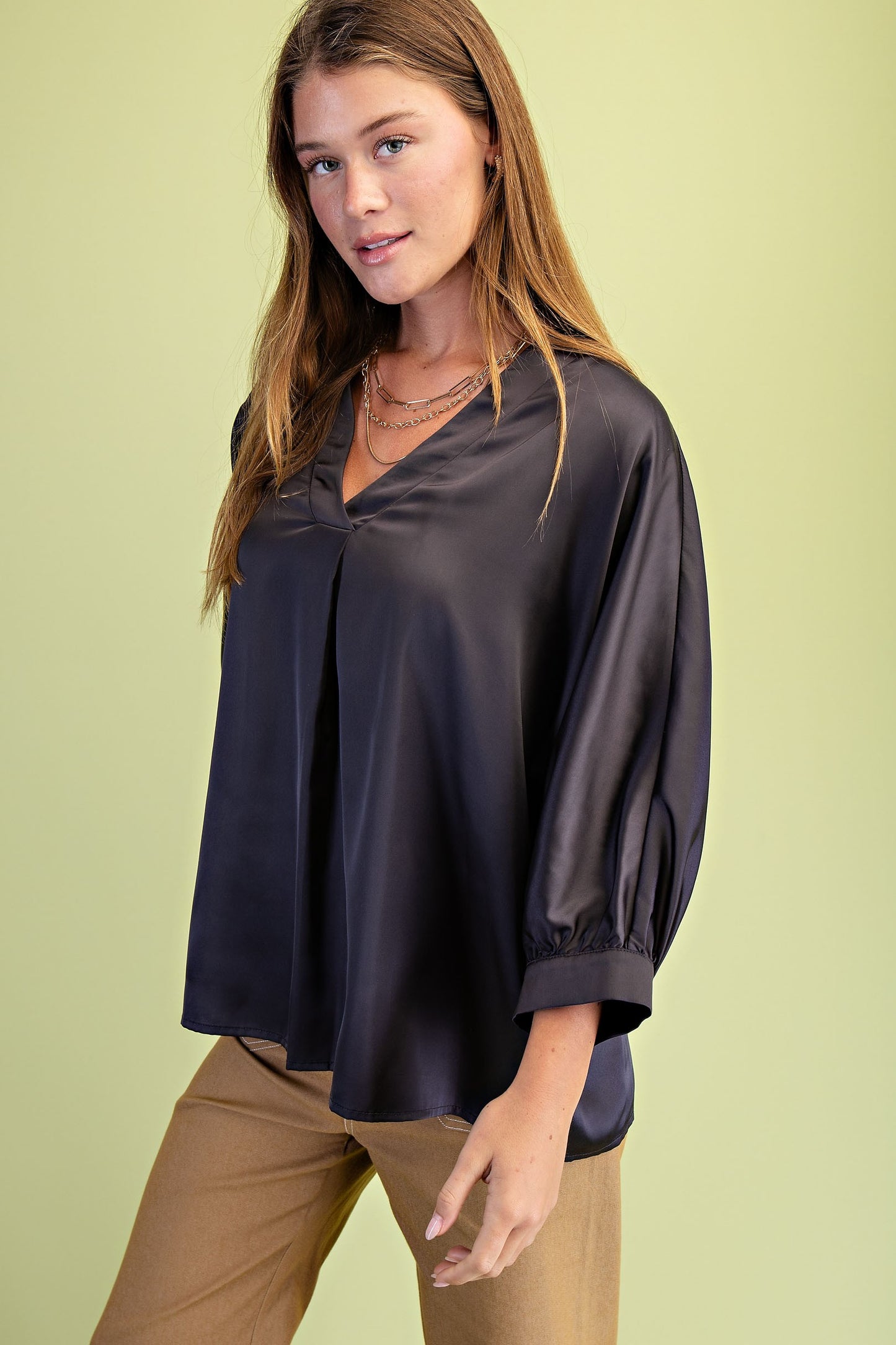 Woman wearing a dark satin blouse against a light green background