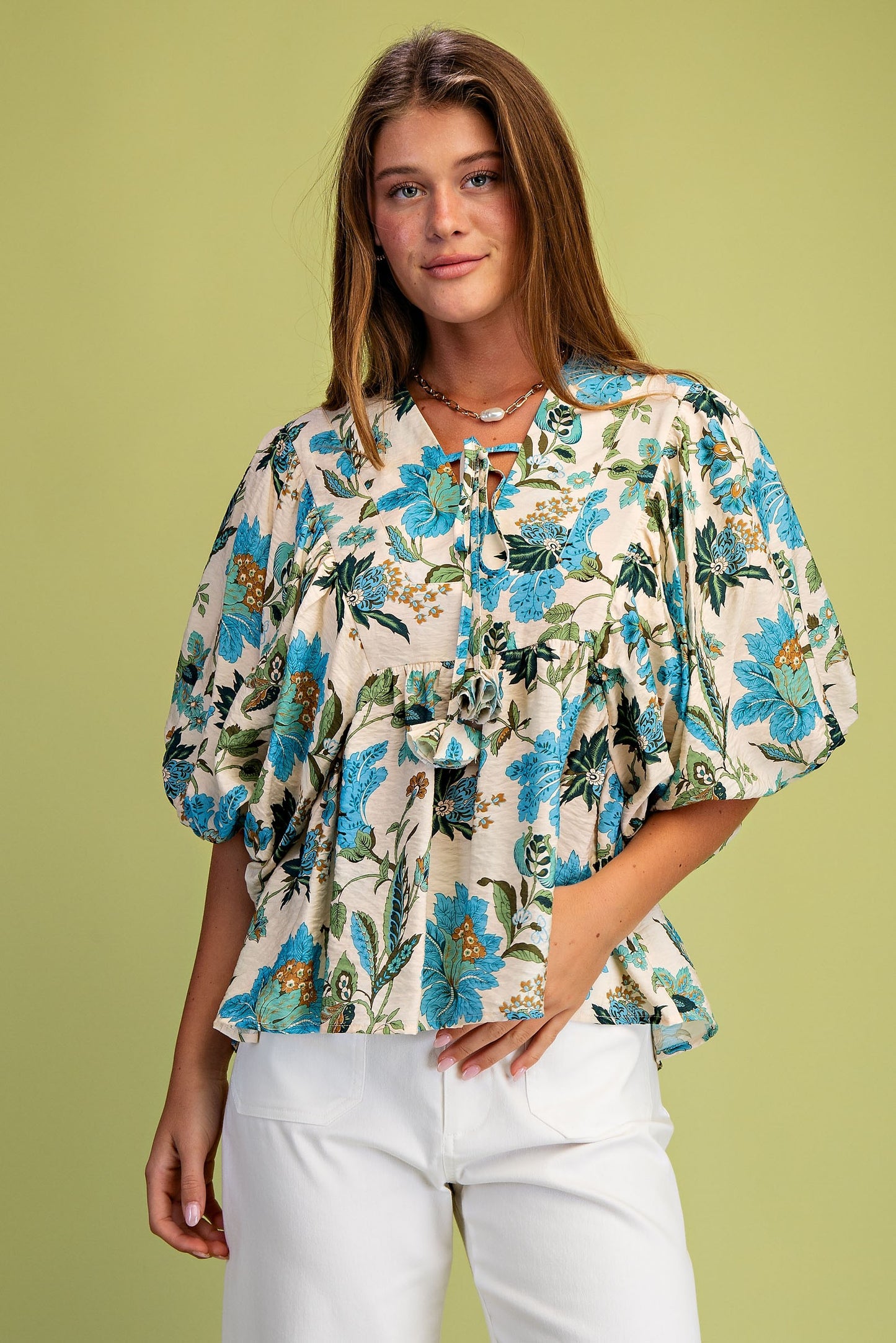 Woman wearing a floral blouse with puff sleeves against a green background