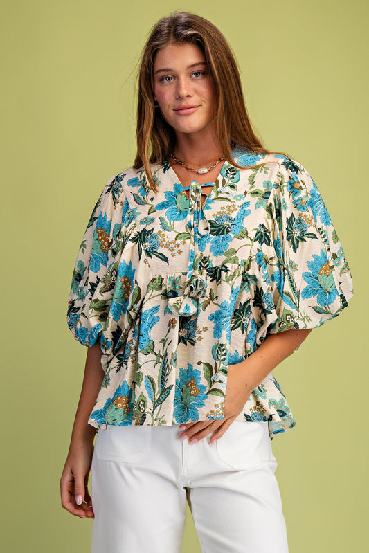 Woman wearing a floral blouse with puff sleeves against a green background