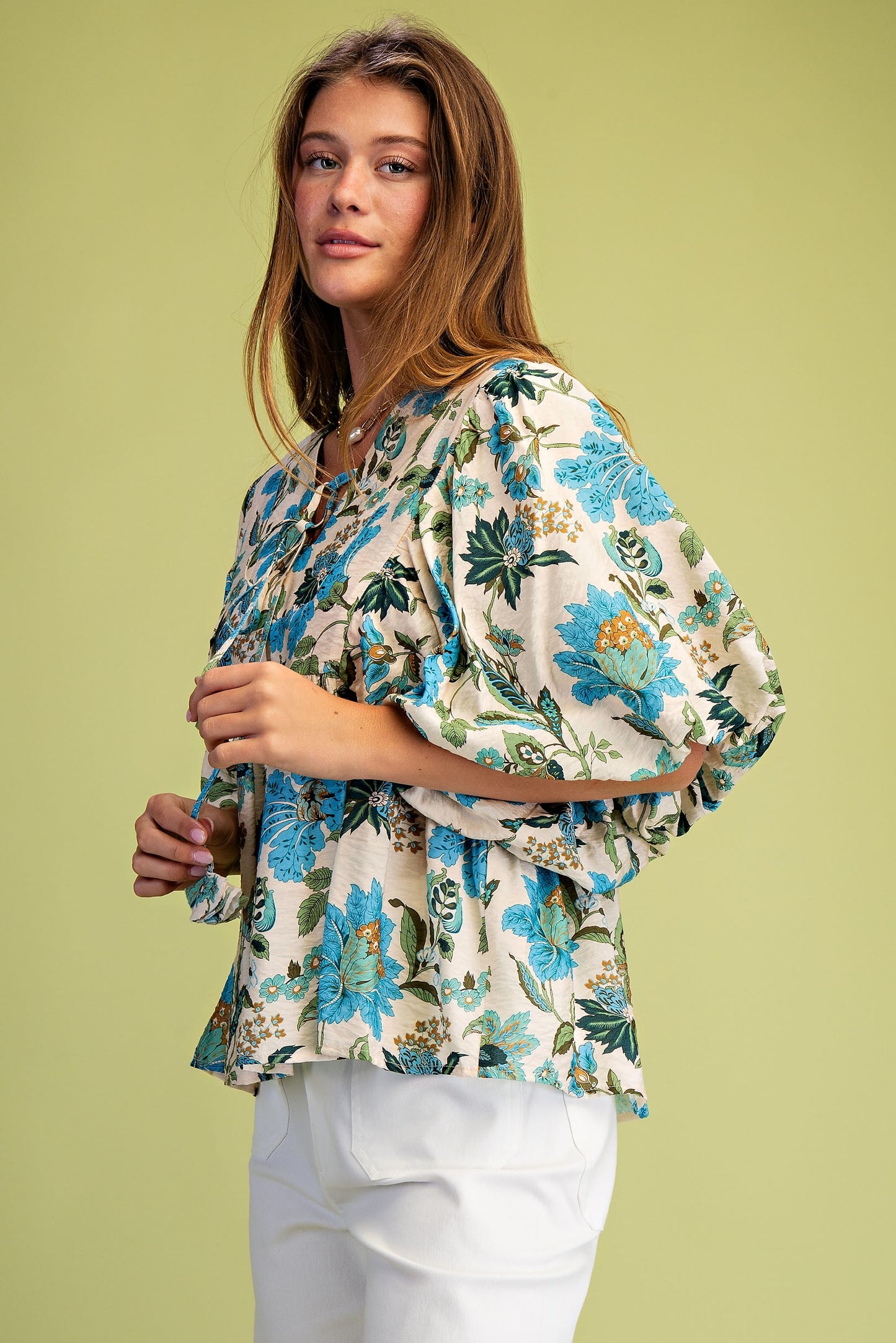 Woman wearing a floral blouse against a green background