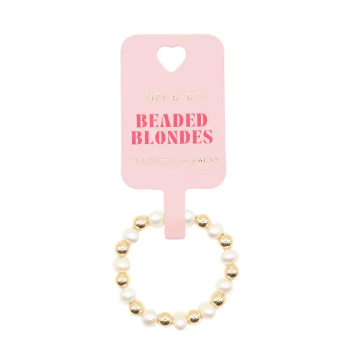 A beaded stretch bracelet with white faux pearls and gold-toned beads, attached to a light pink retail card that reads 'SIZE 6.00 BEADED BLONDES'.