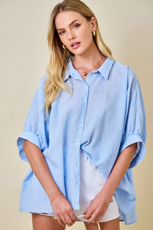 Woman wearing a light blue oversized shirt against a beige background