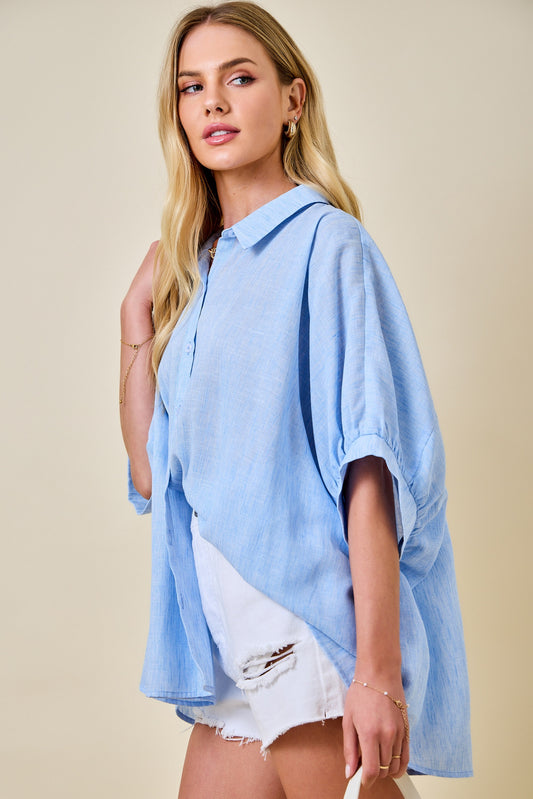 Woman wearing a light blue oversized shirt with a beige background