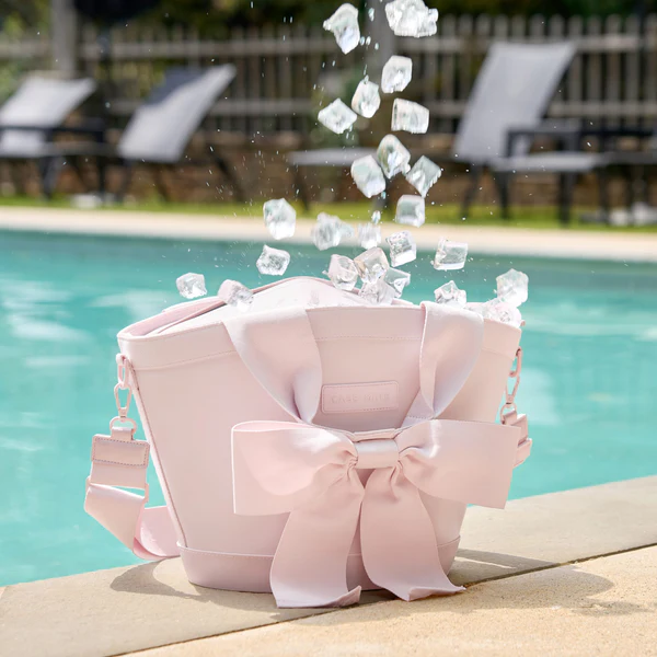 Casemate pink mini cooler with bow strap with ice coming out in front of pool