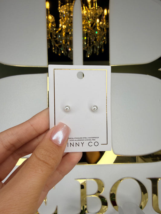 Hand holding a card with earrings and 'INNY CO' branding against a decorative background.