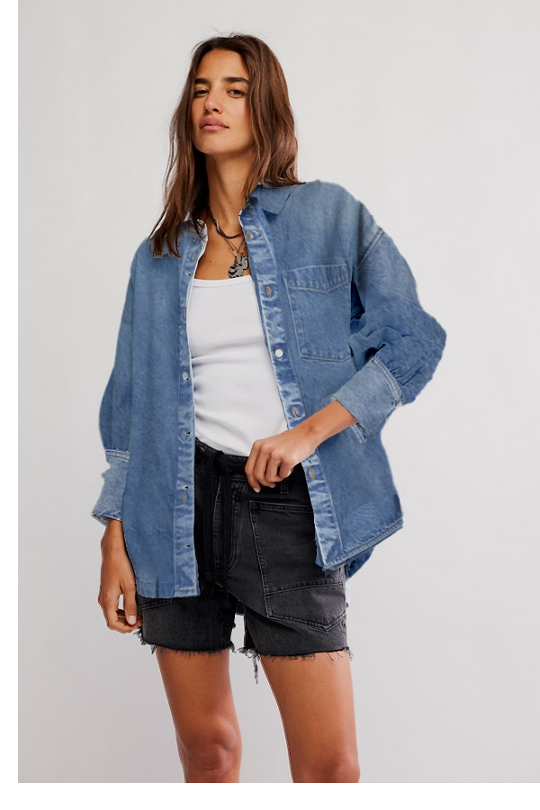 Woman wearing a denim jacket over a white top and black shorts on a light gray background