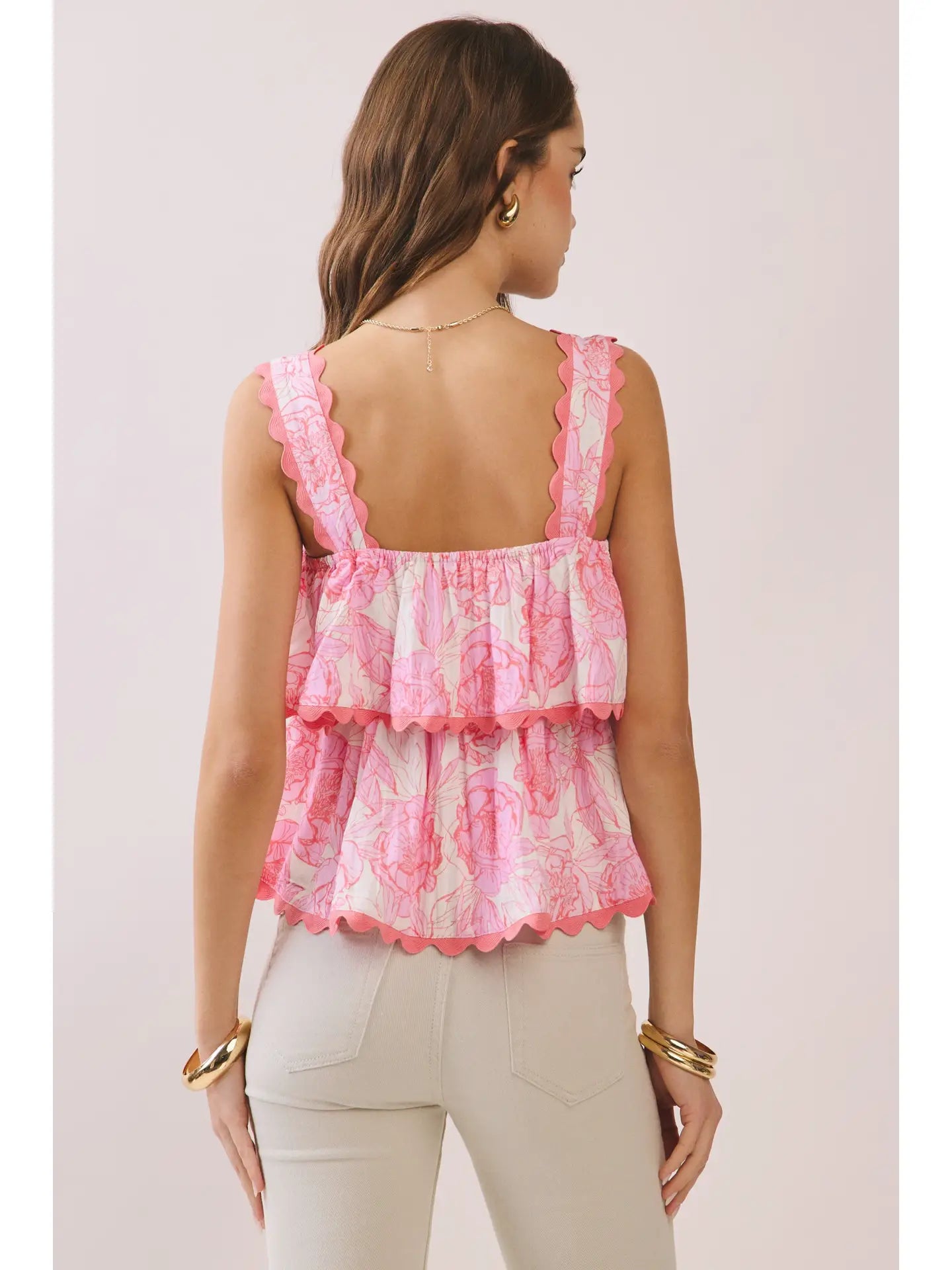 Woman wearing a pink lace top with ruffled details on a light pink background