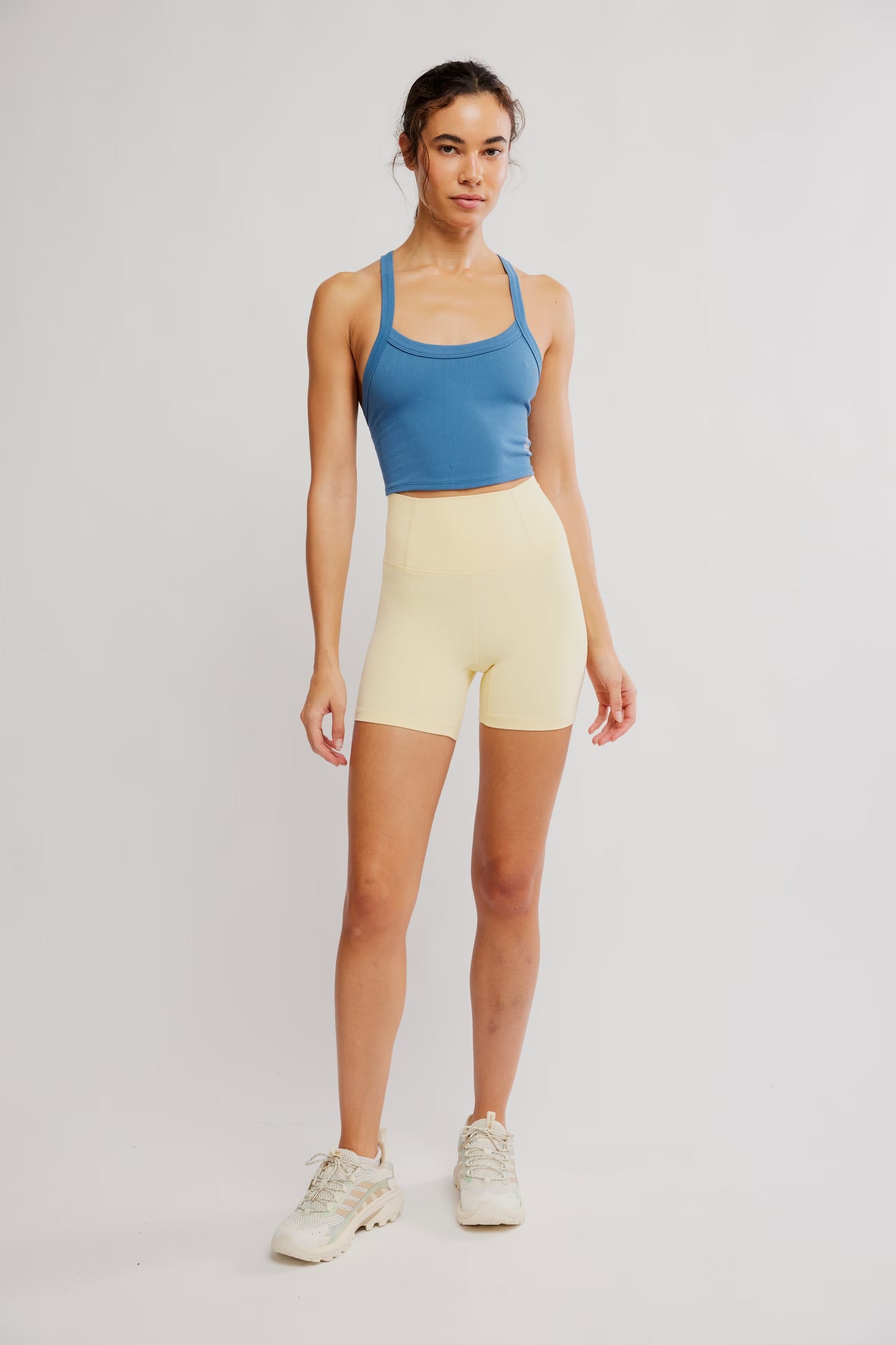 Woman wearing a blue tank top and yellow shorts on a white background