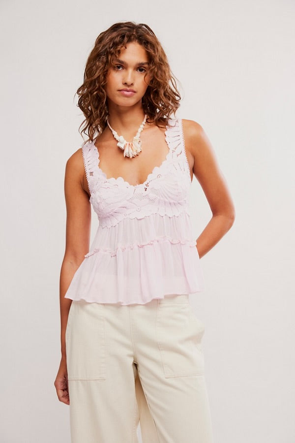 Woman wearing a white ruffled top and light-colored pants against a plain background