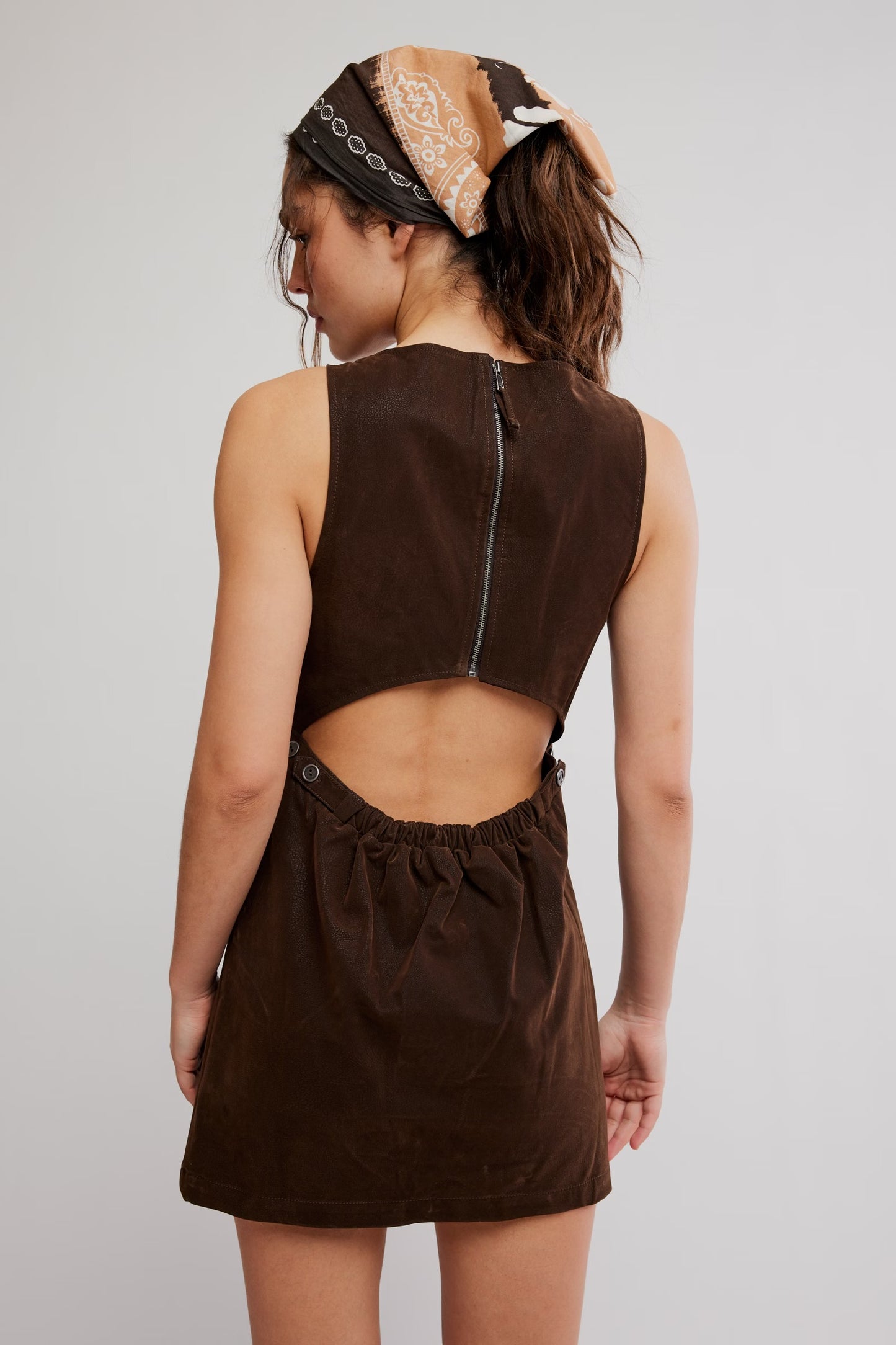 model wearing brown suede mini dress facing the back with hole in the back