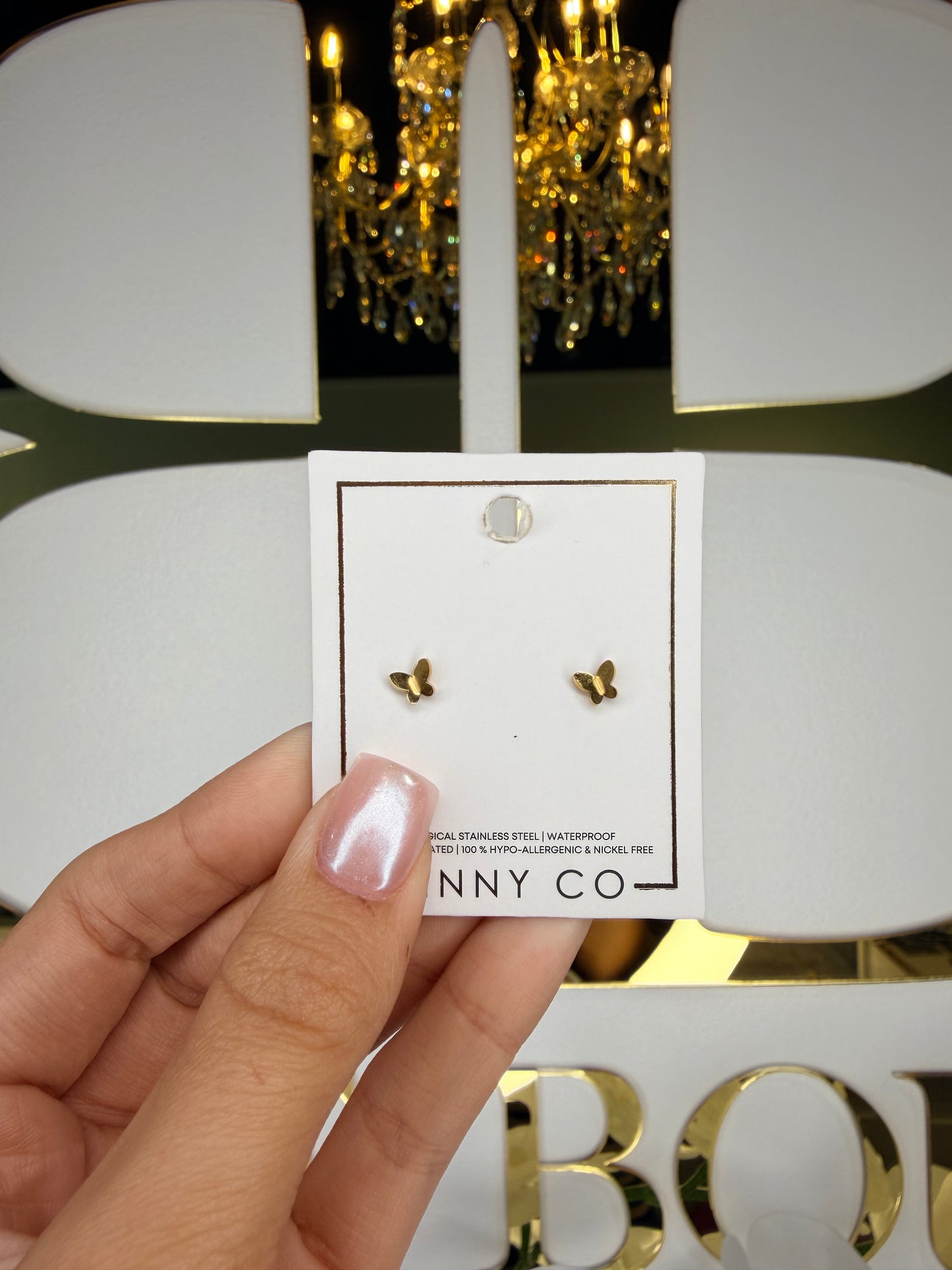 Gold earrings on a card held by a hand with a blurred background