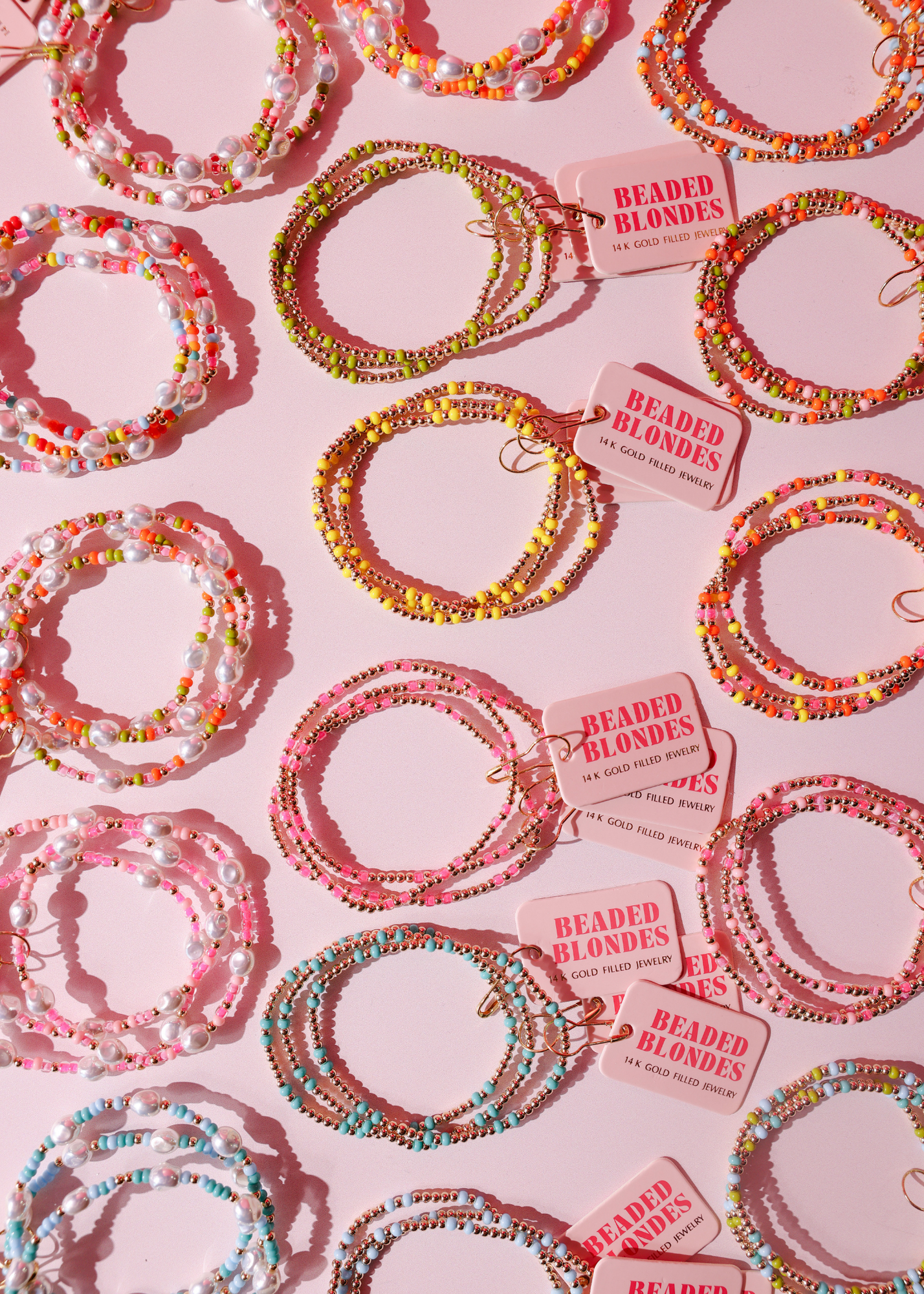 Colorful beaded bracelets on a pink background with 'Beaded Blondes' tags.