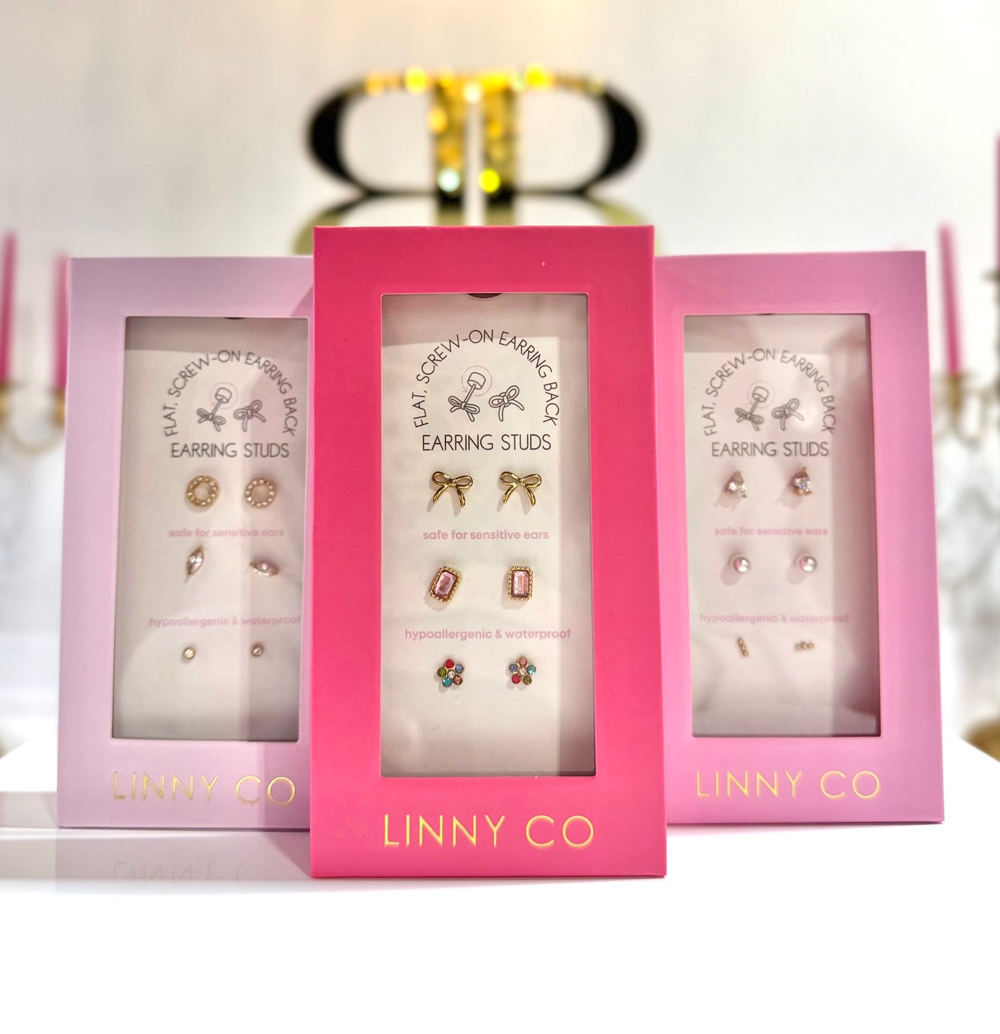 Three pink boxes of Linny Co earrings on a white background