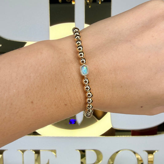 Hand wearing a bracelet with a blurred background featuring decorative elements.