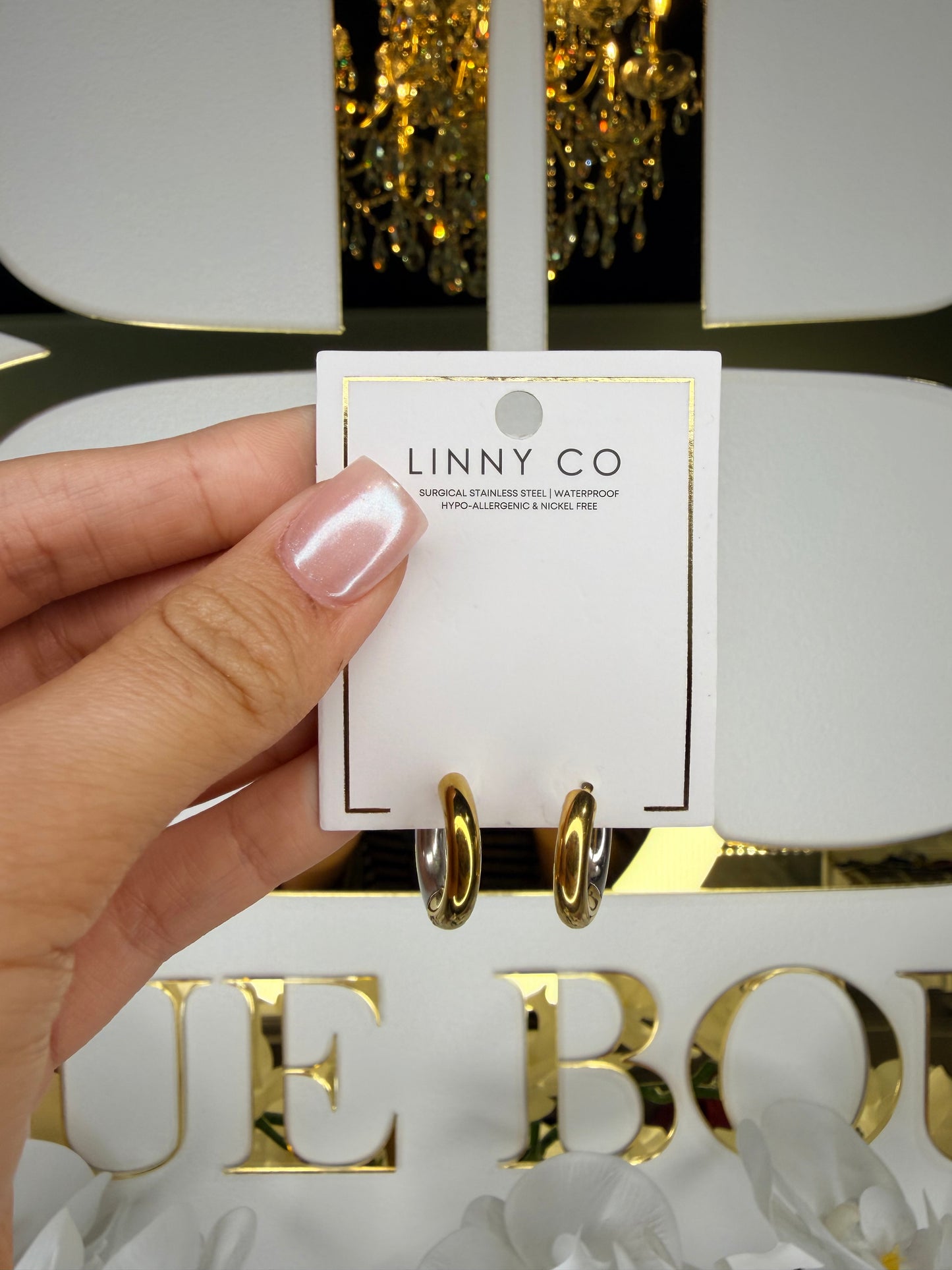 Hand holding a card with 'LINNY CO' branding in front of a decorative background.