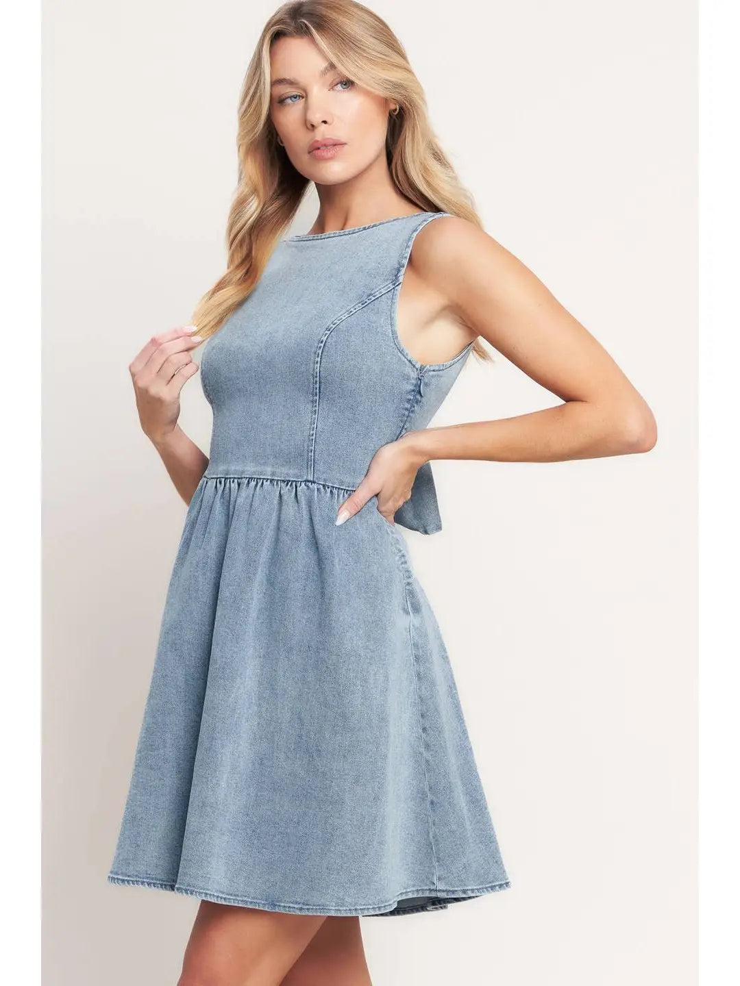 Woman wearing a light blue denim dress against a plain background