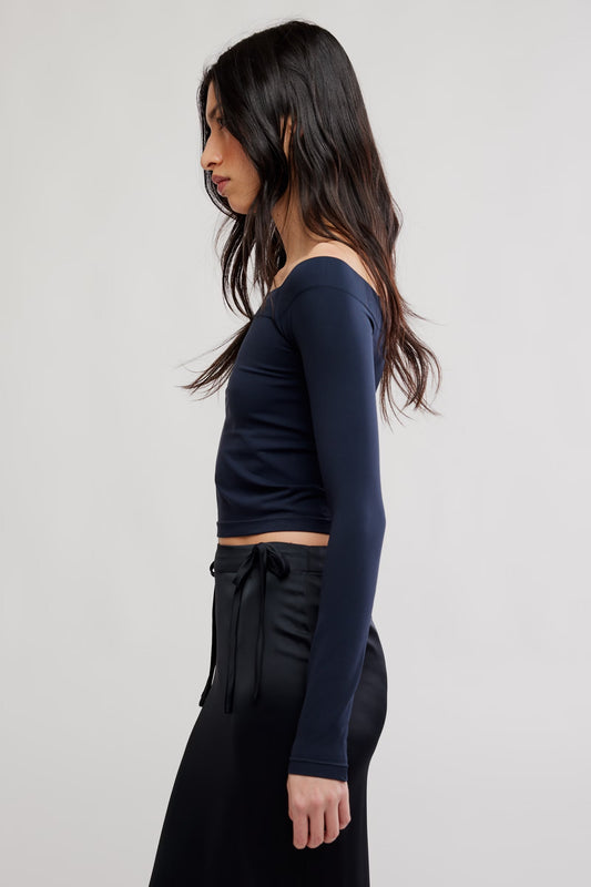 Model wearing black off the shoulder top facing sideways