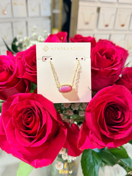 Necklace card with a pink pendant displayed among red roses.