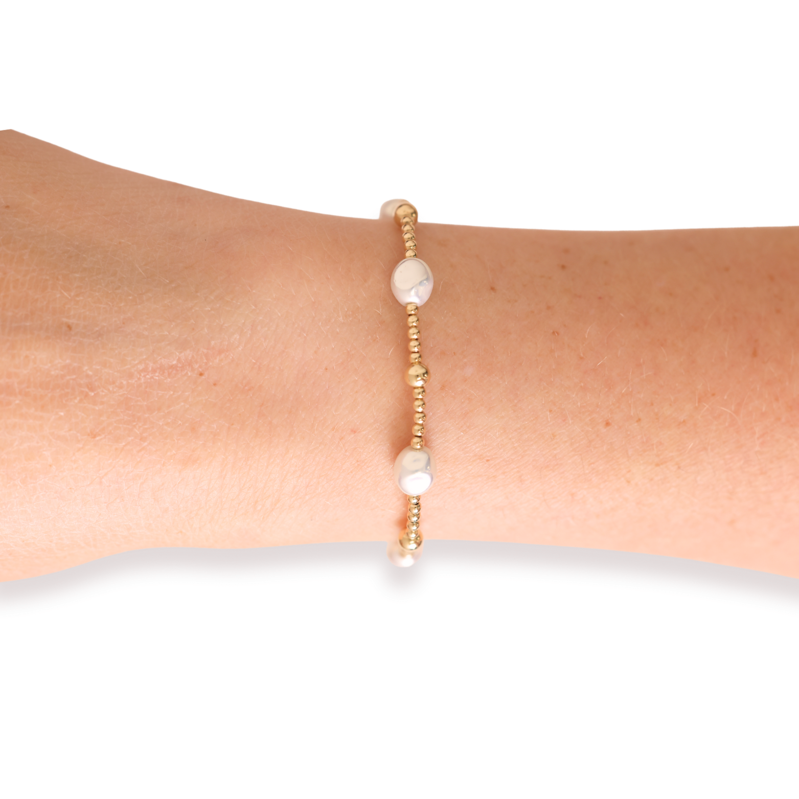 Gold and pearl bracelet on a wrist against a white background