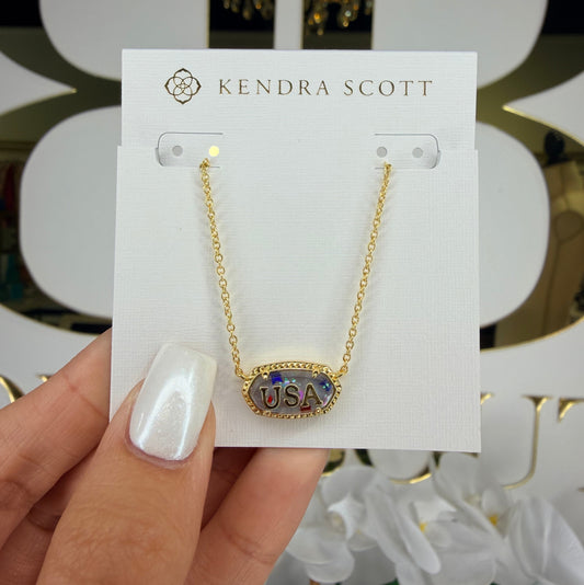 Kendra Scott necklace on a card held by a hand with white nail polish.