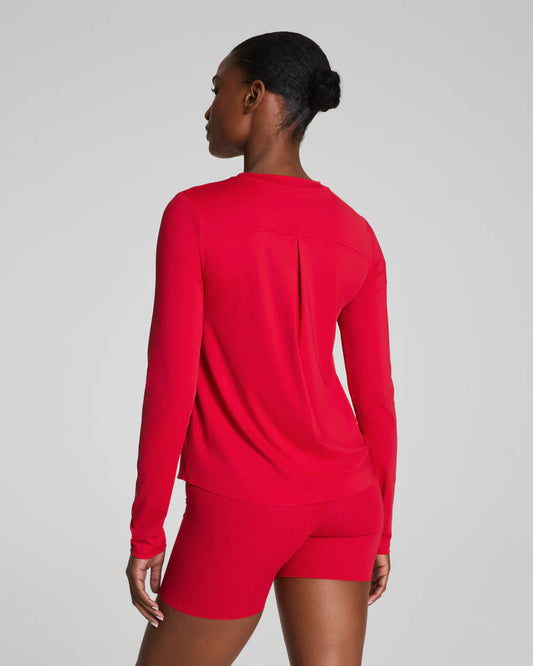 Person wearing a red long-sleeve top and shorts on a gray background