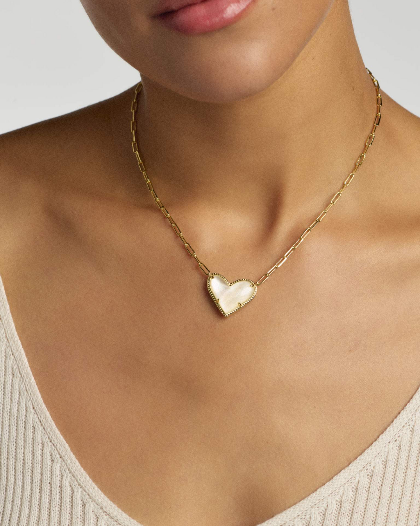 Gold necklace with a heart-shaped pendant worn by a person