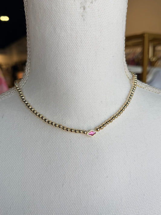 gold beaded kendra Scott necklace with small pink pendant
